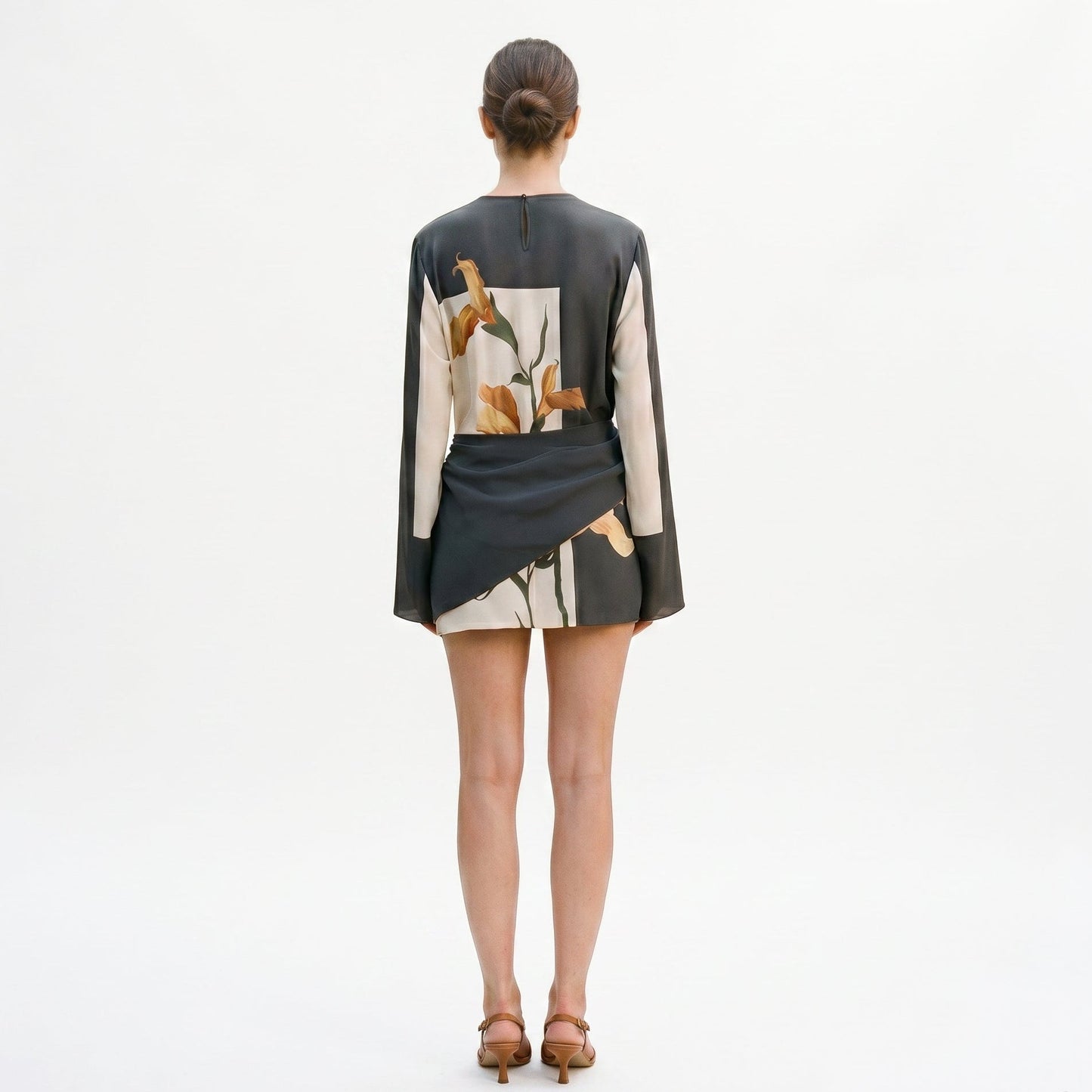 XXL - Model wearing a long-sleeve mini dress featuring a large-scale botanical print, high neckline, and an architectural twisted waist detail.
