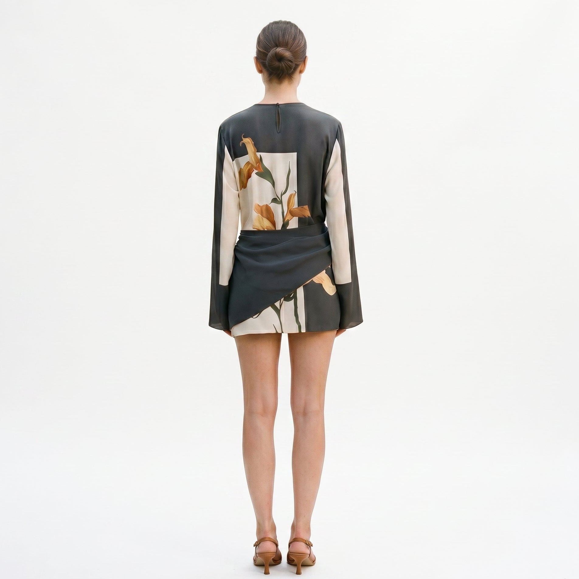 XXL - Model wearing a long-sleeve mini dress featuring a large-scale botanical print, high neckline, and an architectural twisted waist detail.