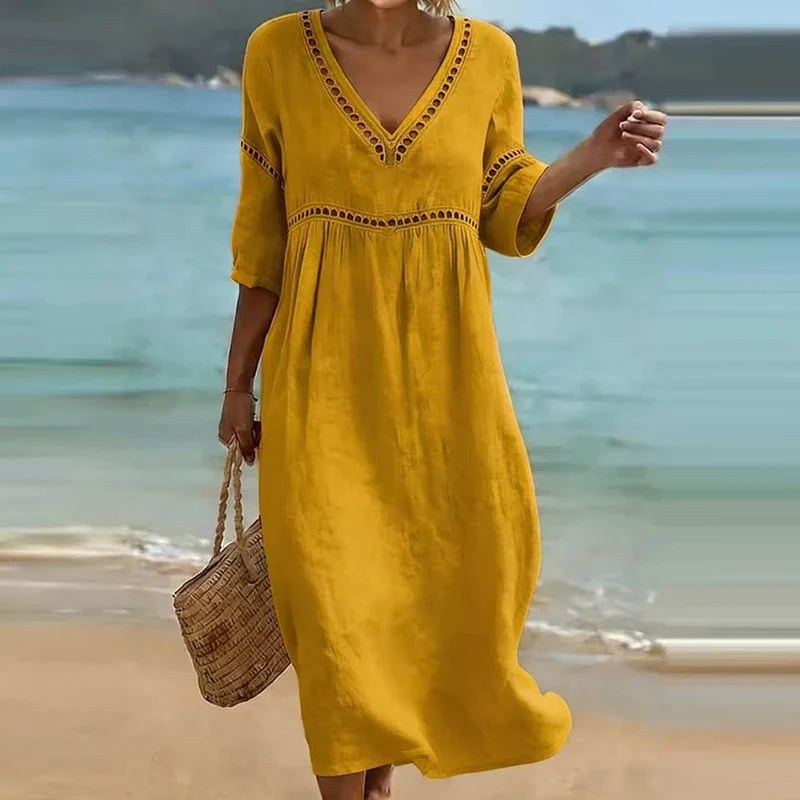 Woman walking on a beach wearing a solid colored midi dress with half sleeves, an empire waist, and crochet trim detailing