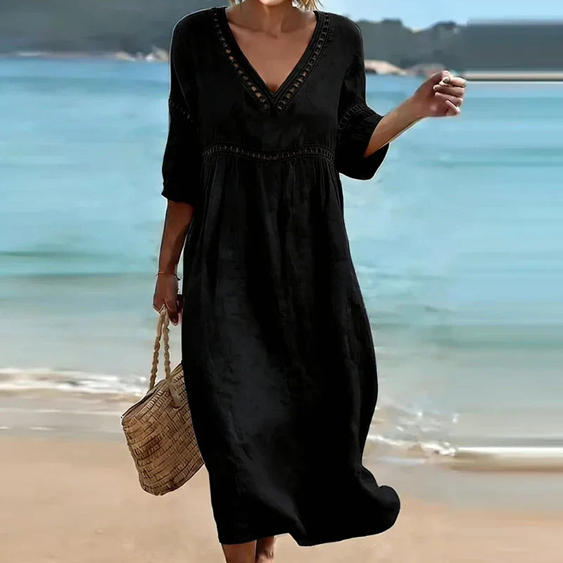 Black - Woman walking on a beach wearing a solid colored midi dress with half sleeves, an empire waist, and crochet trim detailing