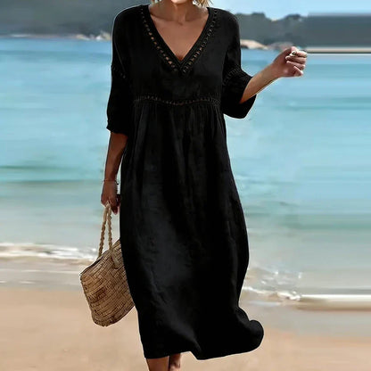 Black - Woman walking on a beach wearing a solid colored midi dress with half sleeves, an empire waist, and crochet trim detailing