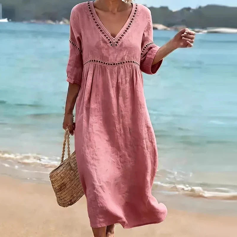 Pink - Woman walking on a beach wearing a solid colored midi dress with half sleeves, an empire waist, and crochet trim detailing