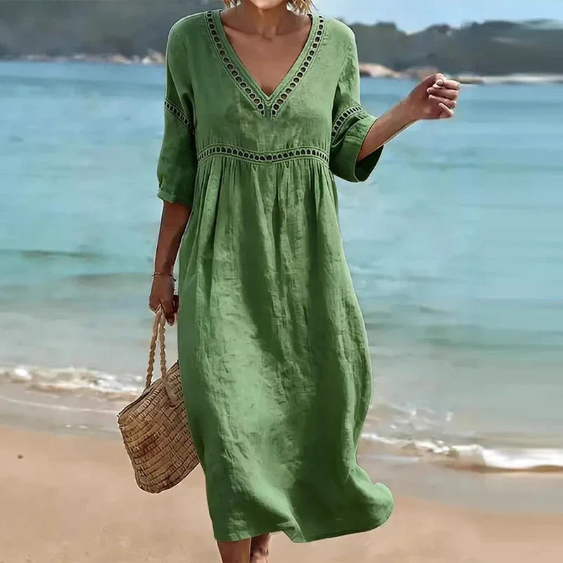 Green - Woman walking on a beach wearing a solid colored midi dress with half sleeves, an empire waist, and crochet trim detailing