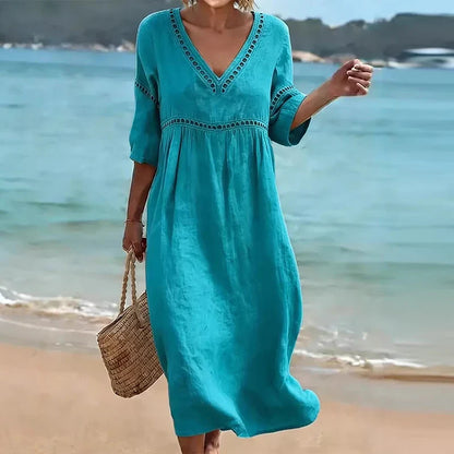 Lake Blue - Woman walking on a beach wearing a solid colored midi dress with half sleeves, an empire waist, and crochet trim detailing