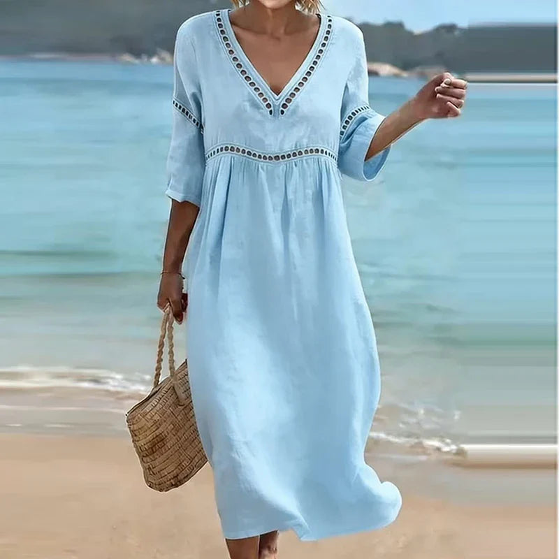 Light Blue - Woman walking on a beach wearing a solid colored midi dress with half sleeves, an empire waist, and crochet trim detailing