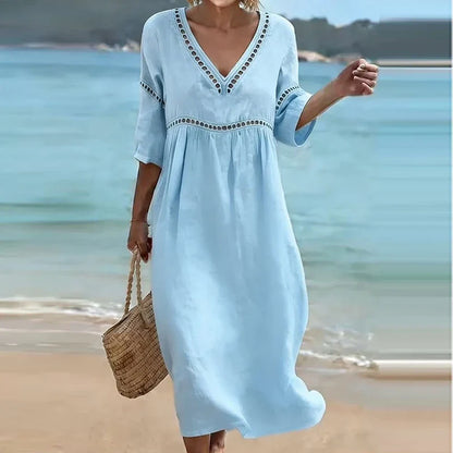 Light Blue - Woman walking on a beach wearing a solid colored midi dress with half sleeves, an empire waist, and crochet trim detailing