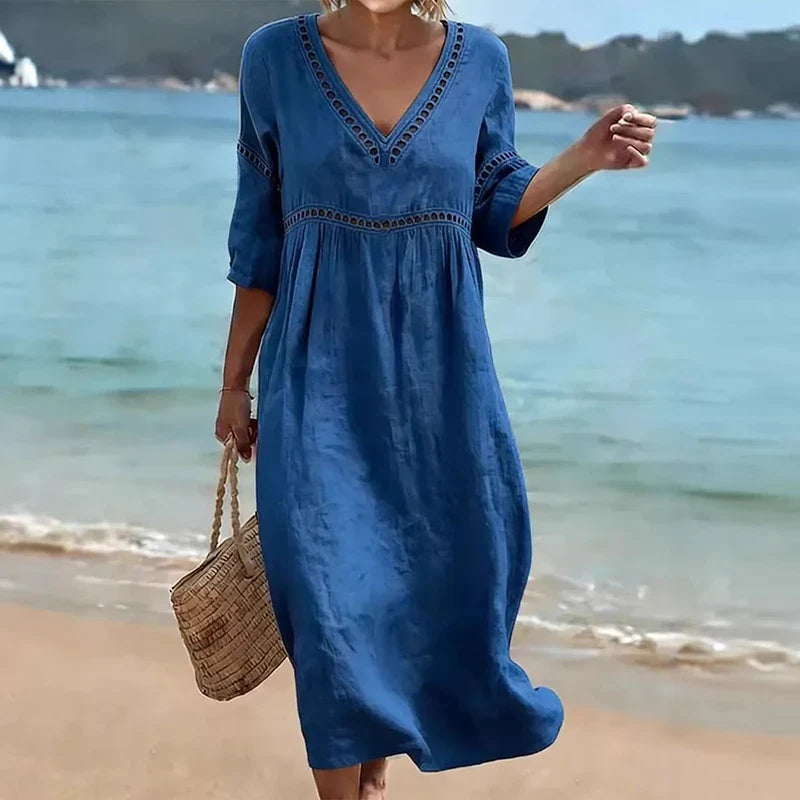 Blue - Woman walking on a beach wearing a solid colored midi dress with half sleeves, an empire waist, and crochet trim detailing