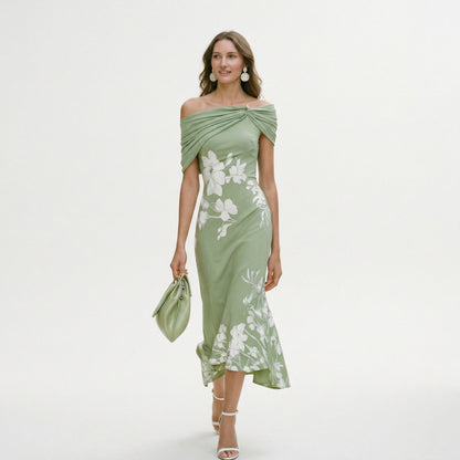 Green - Model wearing a green floral off-shoulder midi dress with a draped neckline and asymmetrical hem, holding a matching clutch.