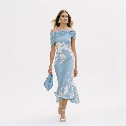 Blue - Model wearing a green floral off-shoulder midi dress with a draped neckline and asymmetrical hem, holding a matching clutch.