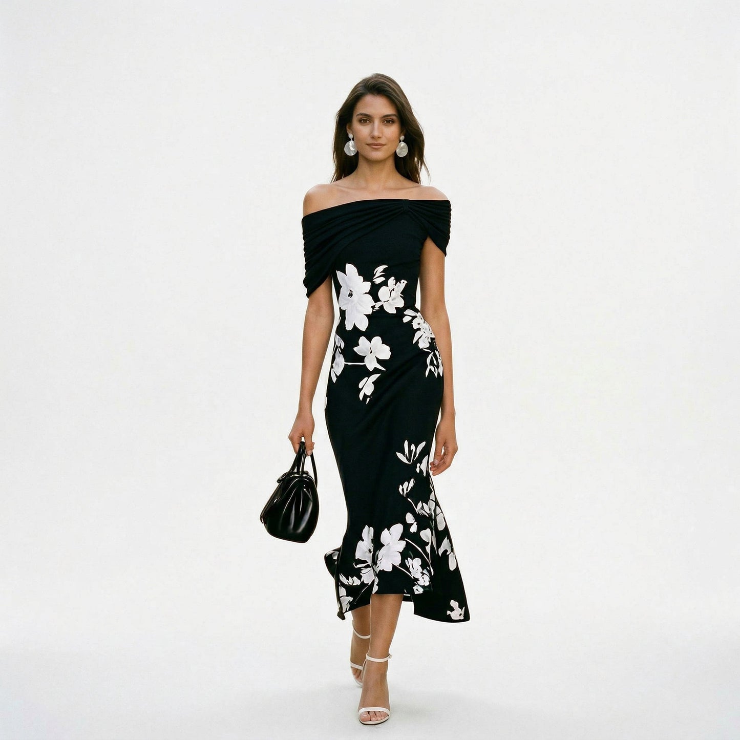 Black - Model wearing a green floral off-shoulder midi dress with a draped neckline and asymmetrical hem, holding a matching clutch.