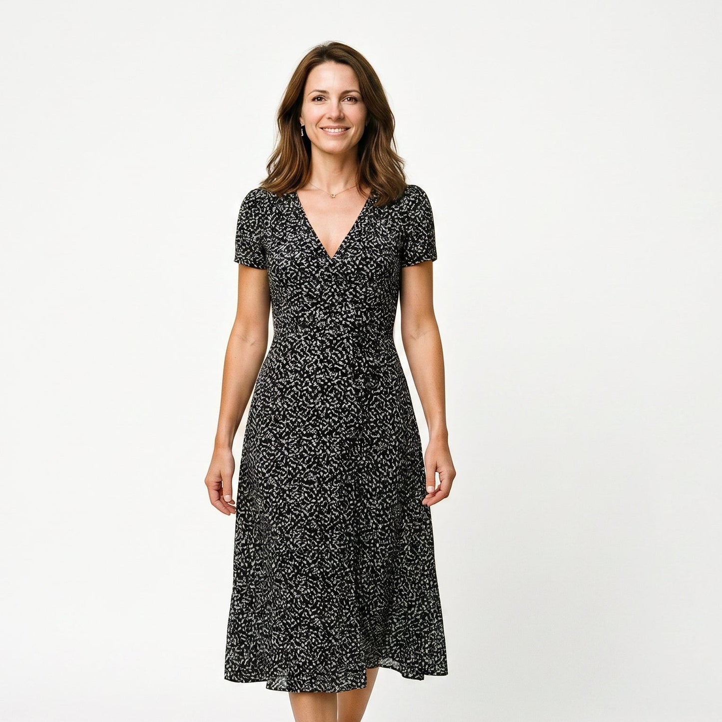 Black - Woman wearing a floral print midi dress featuring a V-neckline, short puff sleeves, and a flowing skirt.