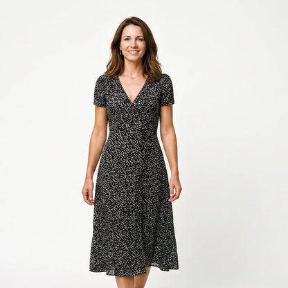 Black - Woman wearing a floral print midi dress featuring a V-neckline, short puff sleeves, and a flowing skirt.