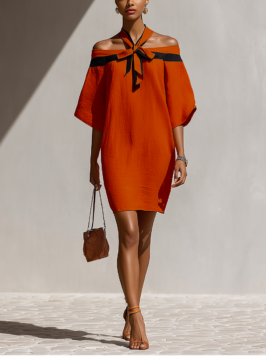 Orange - Model walking outdoors wearing a relaxed textured shift mini dress featuring a contrast halter tie neckline and draped off-the-shoulder sleeves.
