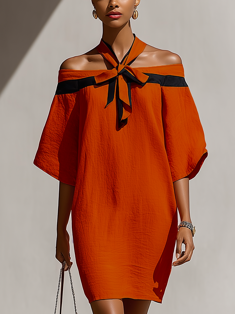 Orange - Model walking outdoors wearing a relaxed textured shift mini dress featuring a contrast halter tie neckline and draped off-the-shoulder sleeves.
