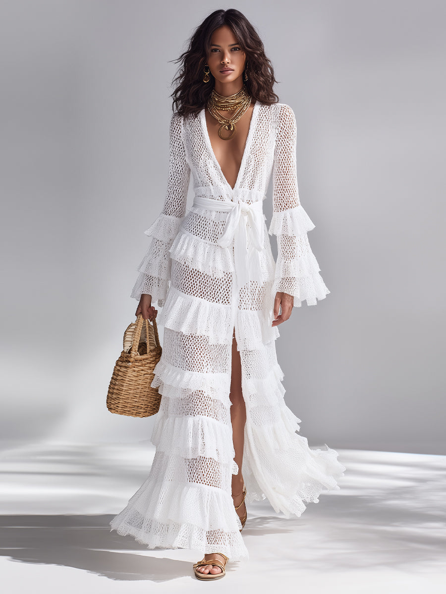 White - Woman wearing a crochet tiered maxi dress with long bell sleeves, a plunging neckline, and a waist tie, holding a woven basket bag