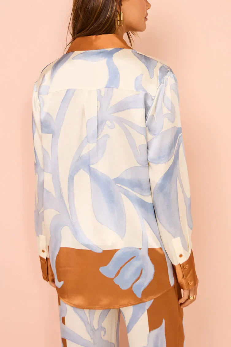 Woman in ivory, brown, and blue floral satin pajama set