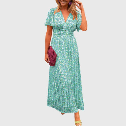 Green - A woman wearing an orange and pink ditsy floral print maxi dress with a V-neckline, flutter sleeves, and a ruched empire waist.