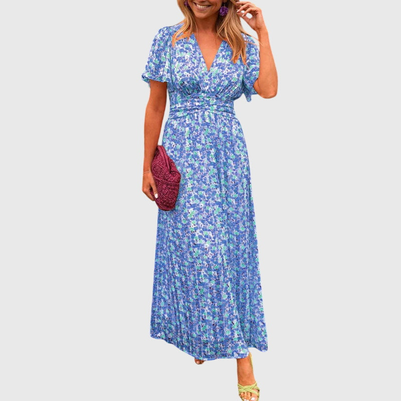 Blue - A woman wearing an orange and pink ditsy floral print maxi dress with a V-neckline, flutter sleeves, and a ruched empire waist.