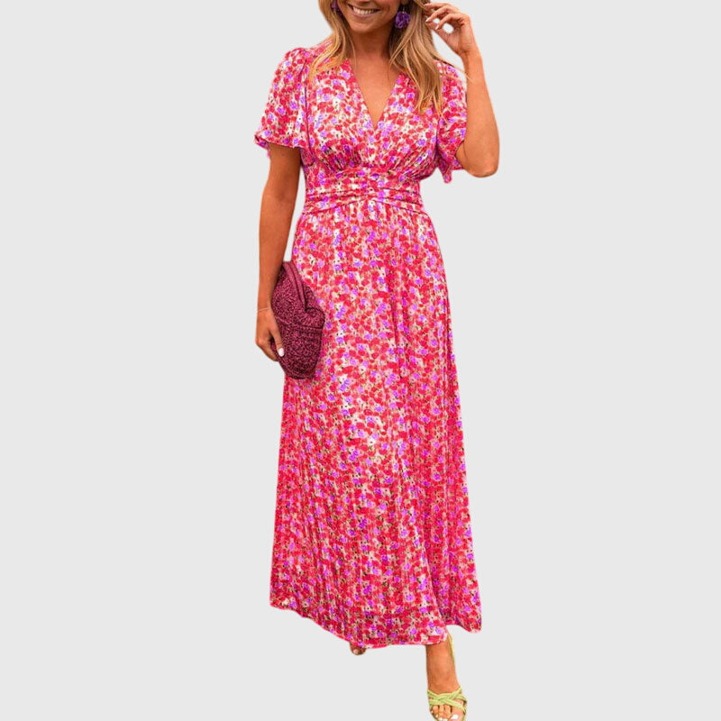 Orange - A woman wearing an orange and pink ditsy floral print maxi dress with a V-neckline, flutter sleeves, and a ruched empire waist.