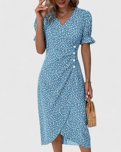 Blue - A woman wearing a green midi dress with a white ditsy floral print, featuring short puff sleeves, a V-neckline, and decorative side buttons with a ruched wrap skirt.