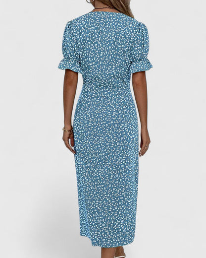 Blue - A woman wearing a green midi dress with a white ditsy floral print, featuring short puff sleeves, a V-neckline, and decorative side buttons with a ruched wrap skirt.