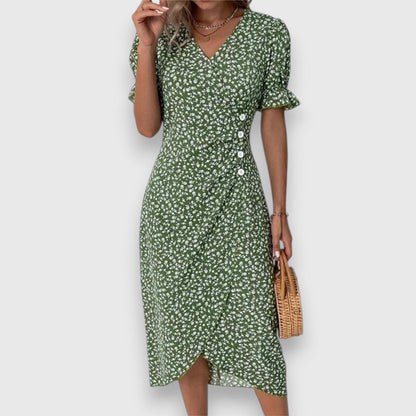 Green - A woman wearing a light blue midi sundress with a white ditsy floral print, featuring puff sleeves, a V-neckline, and an asymmetrical wrap skirt with button details.
