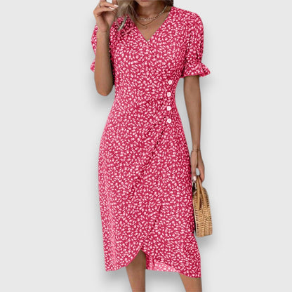 Red - A woman wearing a light blue midi sundress with a white ditsy floral print, featuring puff sleeves, a V-neckline, and an asymmetrical wrap skirt with button details.