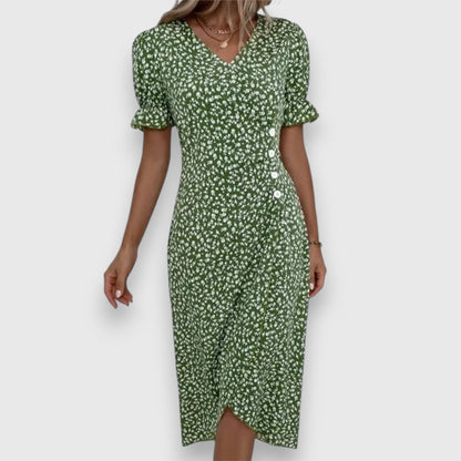 Black - A woman wearing a light blue midi sundress with a white ditsy floral print, featuring puff sleeves, a V-neckline, and an asymmetrical wrap skirt with button details.