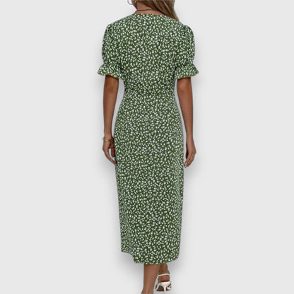 Black - A woman wearing a light blue midi sundress with a white ditsy floral print, featuring puff sleeves, a V-neckline, and an asymmetrical wrap skirt with button details.