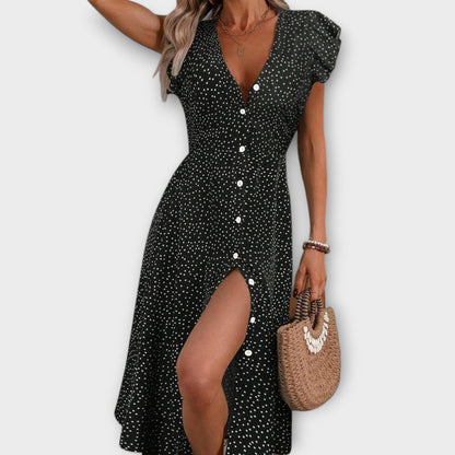 Black - Model wearing a red and white ditsy polka dot midi sundress with a V-neckline, flutter sleeves, and button-down front, paired with a straw hat and white lace-up heels.