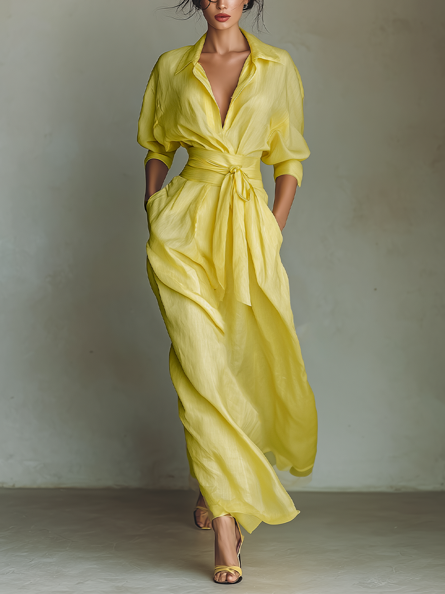 Yellow - Woman walking in a flowing, long-sleeve collared maxi shirtdress with a deep V-neckline and wide waist tie