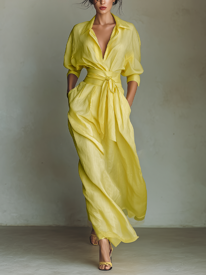 Yellow - Woman walking in a flowing, long-sleeve collared maxi shirtdress with a deep V-neckline and wide waist tie