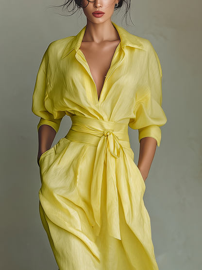 Yellow - Woman walking in a flowing, long-sleeve collared maxi shirtdress with a deep V-neckline and wide waist tie