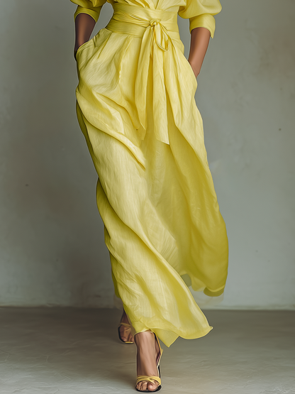 Yellow - Woman walking in a flowing, long-sleeve collared maxi shirtdress with a deep V-neckline and wide waist tie
