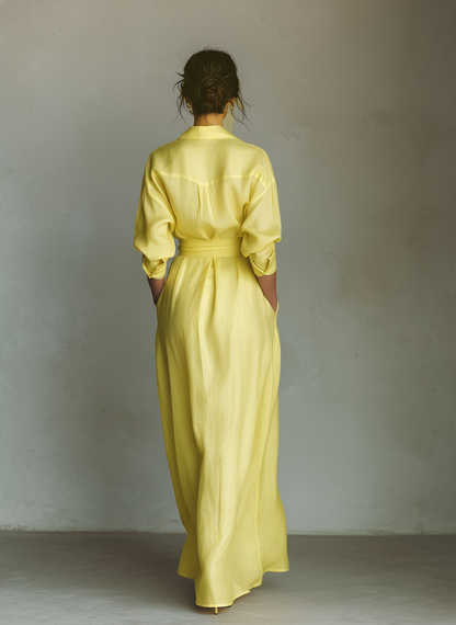 Yellow - Woman walking in a flowing, long-sleeve collared maxi shirtdress with a deep V-neckline and wide waist tie