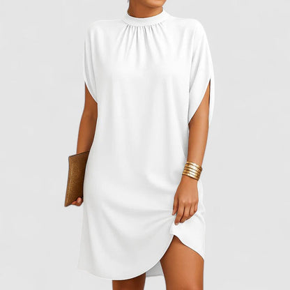 White - A woman wearing a dusty pink crepe shift dress featuring a gathered mock neckline, draped cap sleeves, and a relaxed silhouette.