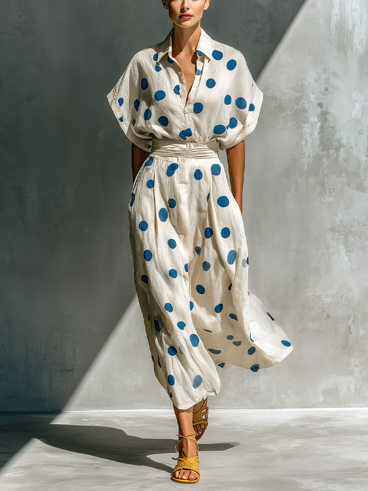 Off-White - Woman walking in a woven polka dot maxi dress with a collared neckline, dolman sleeves, and a wide ruched waistband.