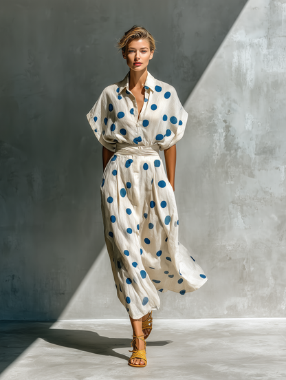 Off-White - Woman walking in a woven polka dot maxi dress with a collared neckline, dolman sleeves, and a wide ruched waistband.
