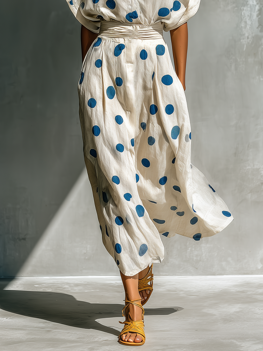Off-White - Woman walking in a woven polka dot maxi dress with a collared neckline, dolman sleeves, and a wide ruched waistband.