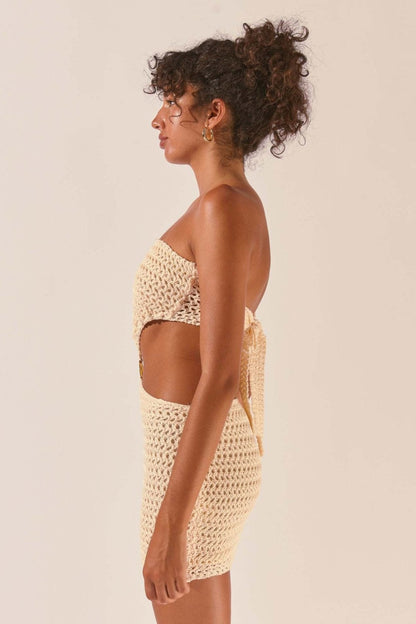 Woman wearing cream crocheted mini dress with cutout waist detail