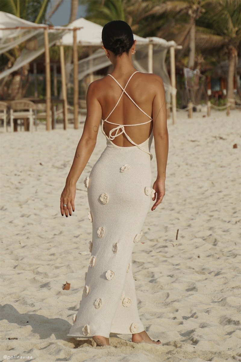 Woman wearing ivory knit maxi dress with floral appliqués