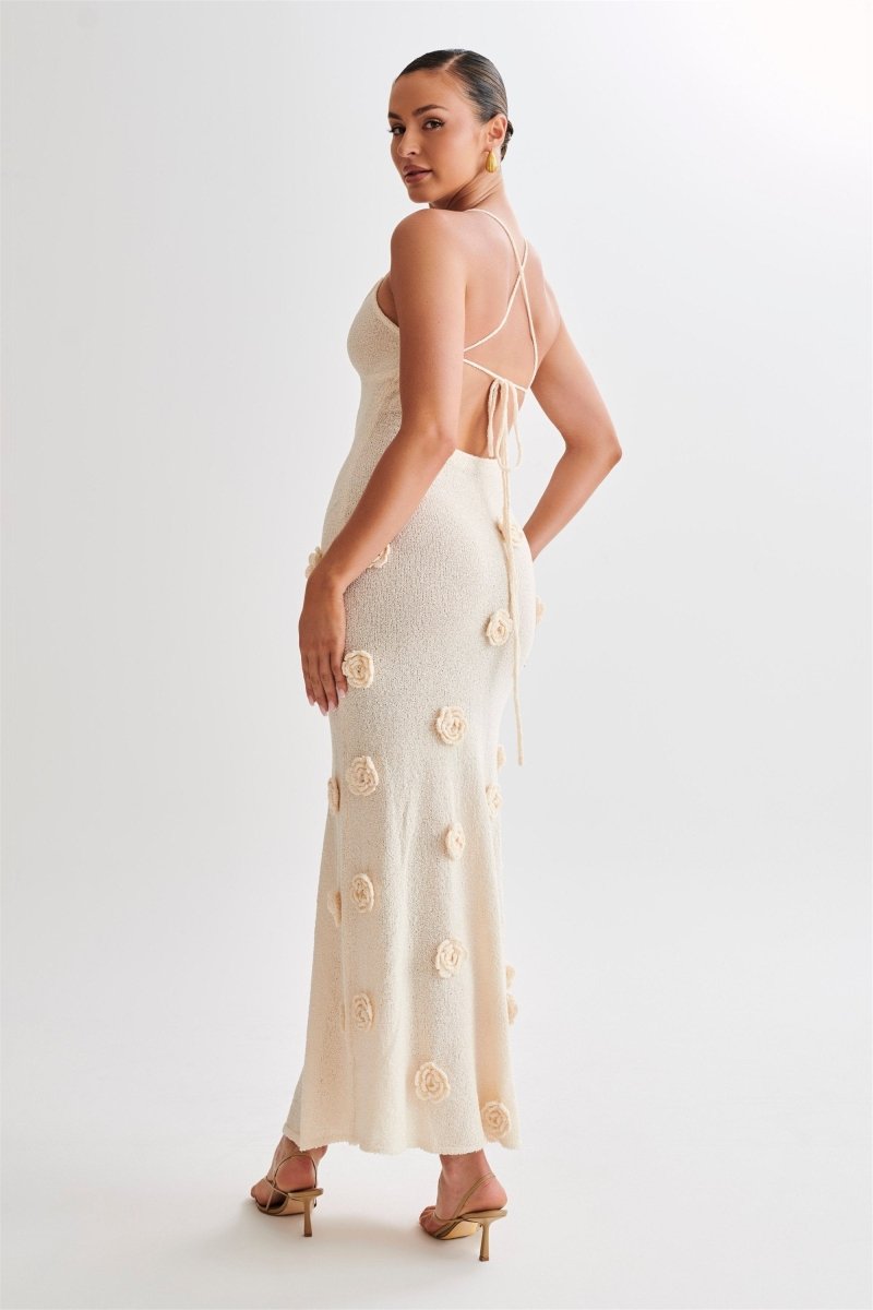 Woman wearing ivory knit maxi dress with floral appliqués