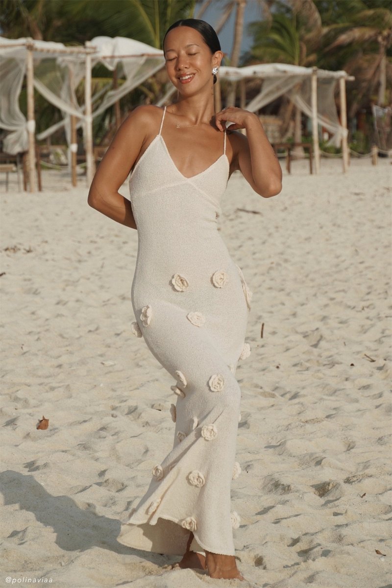 Woman wearing ivory knit maxi dress with floral appliqués