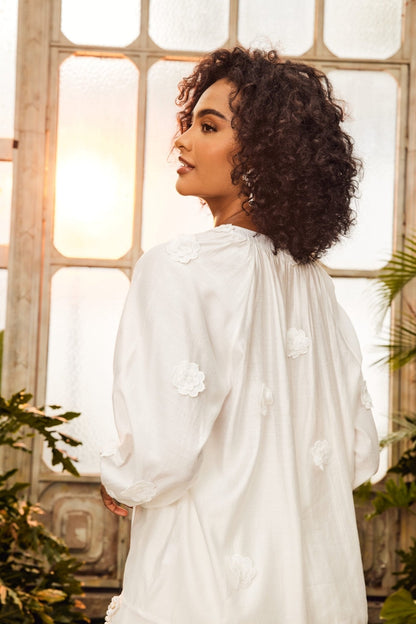 Woman in white floral appliqué blouse and shorts set