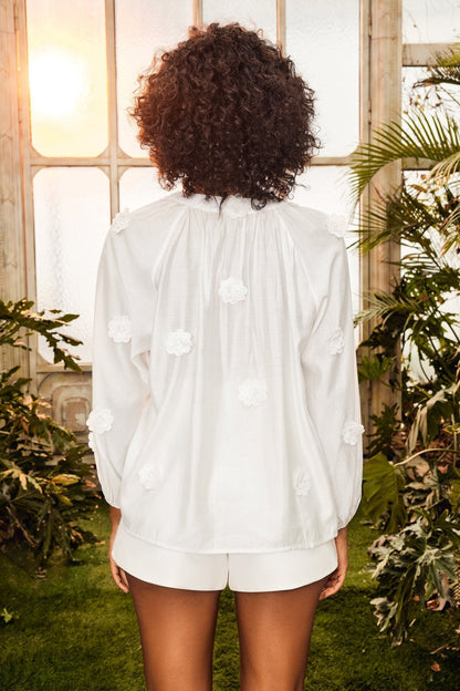 Woman in white floral appliqué blouse and shorts set