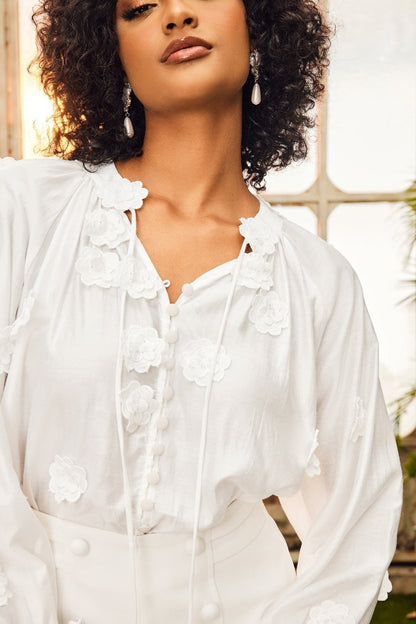 Woman in white floral appliqué blouse and shorts set
