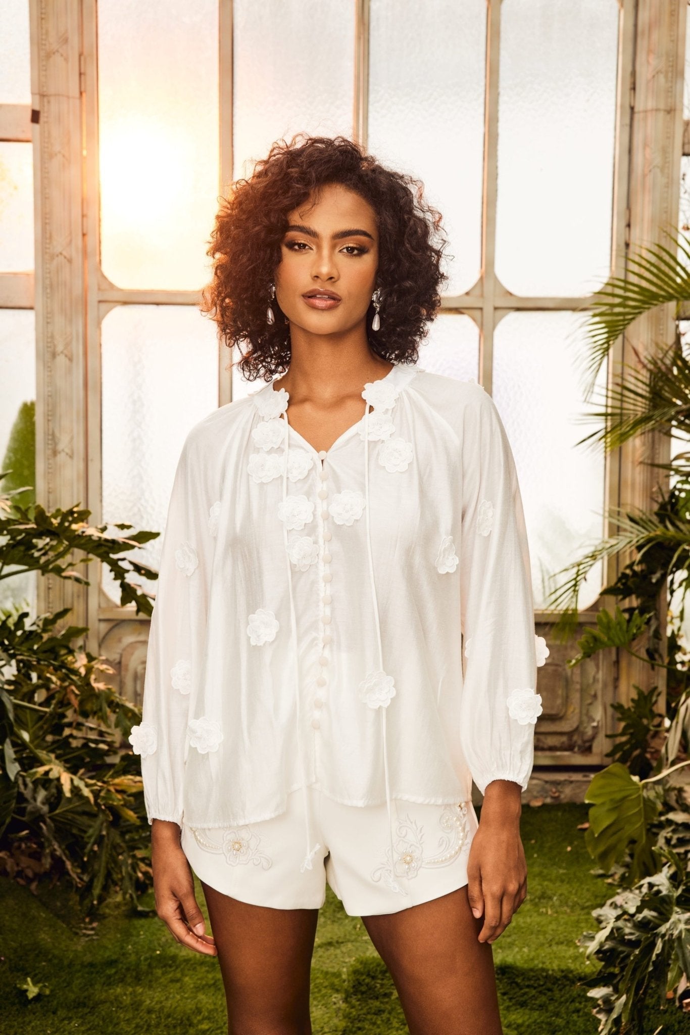 Woman in white floral appliqué blouse and shorts set