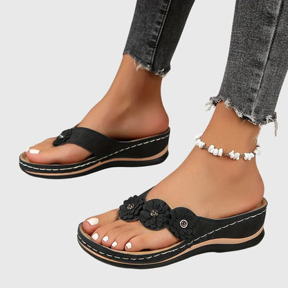 Black - Faux-suede slip-on wedge sandals featuring three floral appliques across the instep, contrast stitching details, and a contoured comfort footbed.