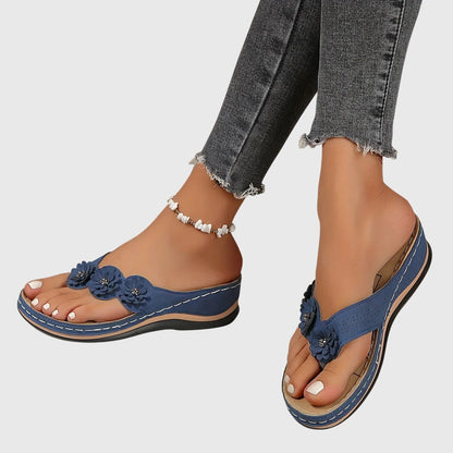 Black - Faux-suede slip-on wedge sandals featuring three floral appliques across the instep, contrast stitching details, and a contoured comfort footbed.