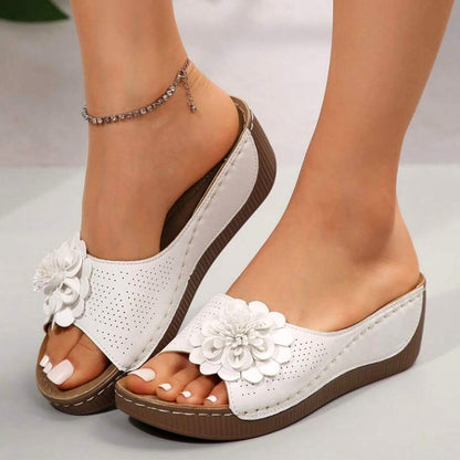White - Women's slip-on wedge sandals featuring a perforated upper with a 3D floral applique and contrast stitching.